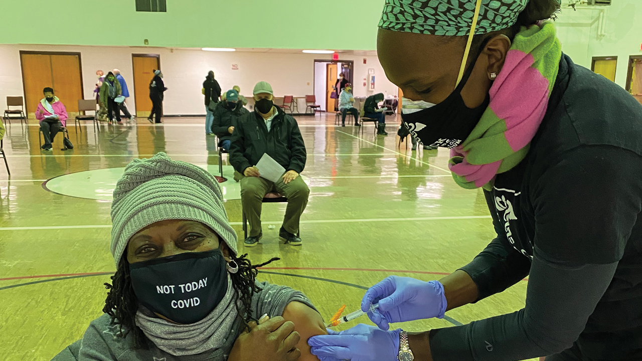 Dr. Ala Stanford (standing) delivers a socially distanced COVID-19 vaccination at the Deliverance Evangelistic Church in North Philadelphia.  