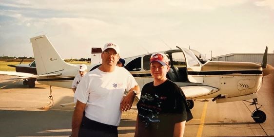 Dr. Hughes with his son circa 2001, in front of a Beechcraft Bonanza airplane