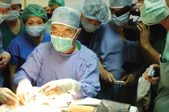 Dr. Jeng (middle, seated) performing an operation as local surgeons watch, Vietnam Military Hospital, Hanoi, in 2009