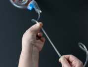 Hold the tubing near your body. Pinch the tube with your other hand and slide your fingers away from your body.