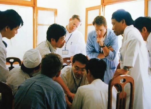 Dr. Jeng (standing, third from left) speaking with local and visiting physicians, Vietnam Military Hospital, Hanoi, in 2002