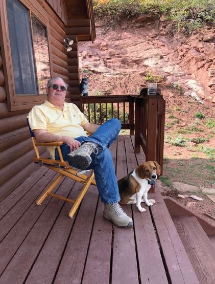 Dr. Hughes relaxing at his cabin in Cuchara, CO, with his “sage advisor,” Cozette the beagle