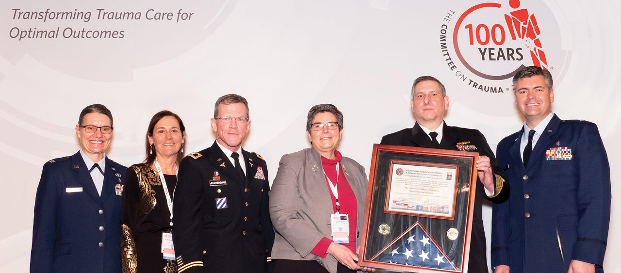 Members of COT Region 13 representing the four branches of the US Armed Forces, present a gift at the COT Annual Meeting recognizing the valued partnership between the ACS COT and the military. From left: Colonel Stacy A. Shackelford, MD, FACS, USAF, MC, Dr. Margaret Knudson, Colonel Jay A. Johannigman, MD, FACS, USAR, Dr. Eileen Bulger, Commander Travis M. Polk, MD, FACS, USN, and Lieutenant Colonel Brian J. Gavitt, MD, MPH, FACS, USAF, MC.